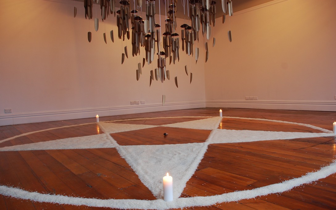 Tiffany Singh, Knock On The Sky Listen To The Sound, 2011, fifty bamboo wind chimes, rice pentagram, candles and white sage smudge stick. Image courtesy of Lance Cash. 