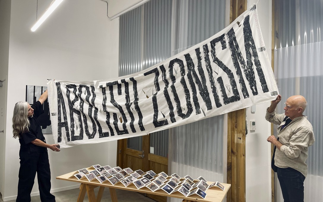 Catherine Griffiths and Bruce Connew hold Abolish Zionism banner, 2024, acrylic on cotton banner. Image courtesy of Jinki Cambronero, 2025.