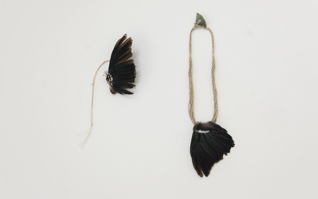 Arawhetu Berdinner, Tāraro tūī - hair adornment, parirau tūī, muka, aute/tapa kōkōwai/preserved tūī wing, flax fibre cordage, barkcloth, earth pigment, 2026 & Tuia, parirau tūī, kōkōwai, muka, inanga pounamu/preserved tūī wing, earth pigment, flax fibre cordage, nephrite jade, 2025. Photo by Samson Dell.  